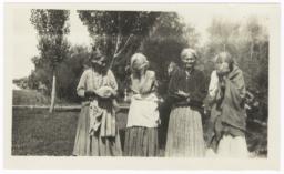 Four Elderly  Women Standing Outside, Two Covering Their Faces from the Camera