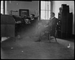 Two Men Sitting in a Office, Reading