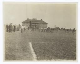 Football Game in Progress with Spectators Standing around the Field's Edge, Haskell Institute