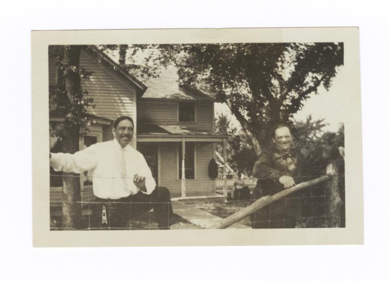 Two Men behind Fence, in front of House