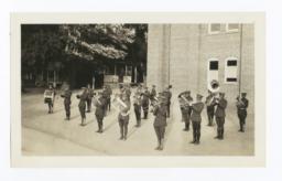 Brass Band in Uniform and Formation to Perform, Gathered in front of a Brick Building