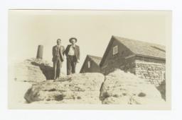 G.E.E. Lindquist and Another Man in a Hat on Rock Outcroppings near Stone Building