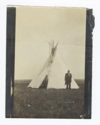 Man in Formal Attire Standing next to a Tipi