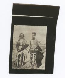 Two Native American Men Wearning Ceremonial Dress, One with Body Paint, Carrying Bow and Arrows  