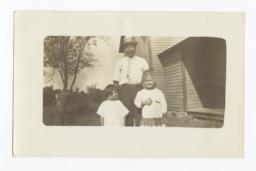 Man and Two Children Outdoors in front of a House