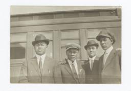 Four Men Wearing Suits and Ties Posing in front of a Building