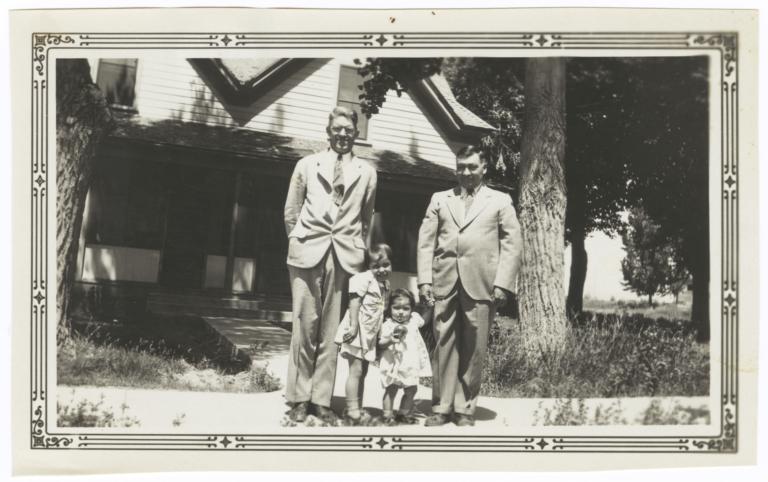 Two Men with Two Children Posing in front of a House