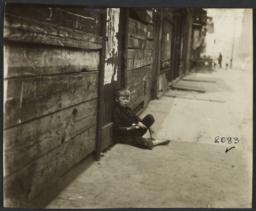 Boy Sitting on Sidewalk
