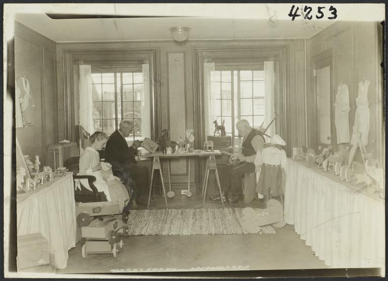 Old Men's Toy Shop Album -- Woman Sewing with Men Making Toys