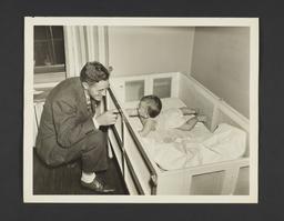 Picturing Some of the Principles of Child Care Album -- Father Plays With Baby in Crib