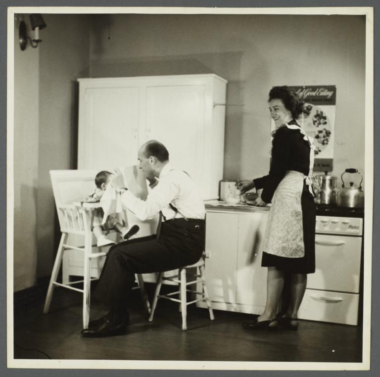 Lenox Hill, 1948-1949 Album -- Man Playing with Baby in High Chair
